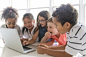 SchülerInnen sitzen gemeinsam vor einem Laptop und lernen