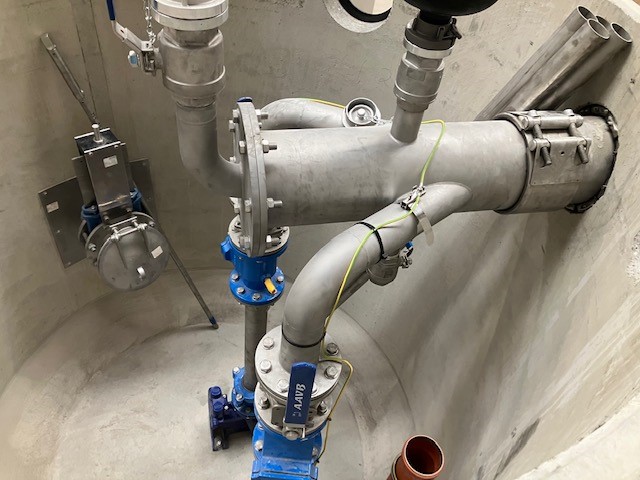 La imagen muestra el funcionamiento interno de una estación de bombeo con varias bombas, válvulas y tuberías.