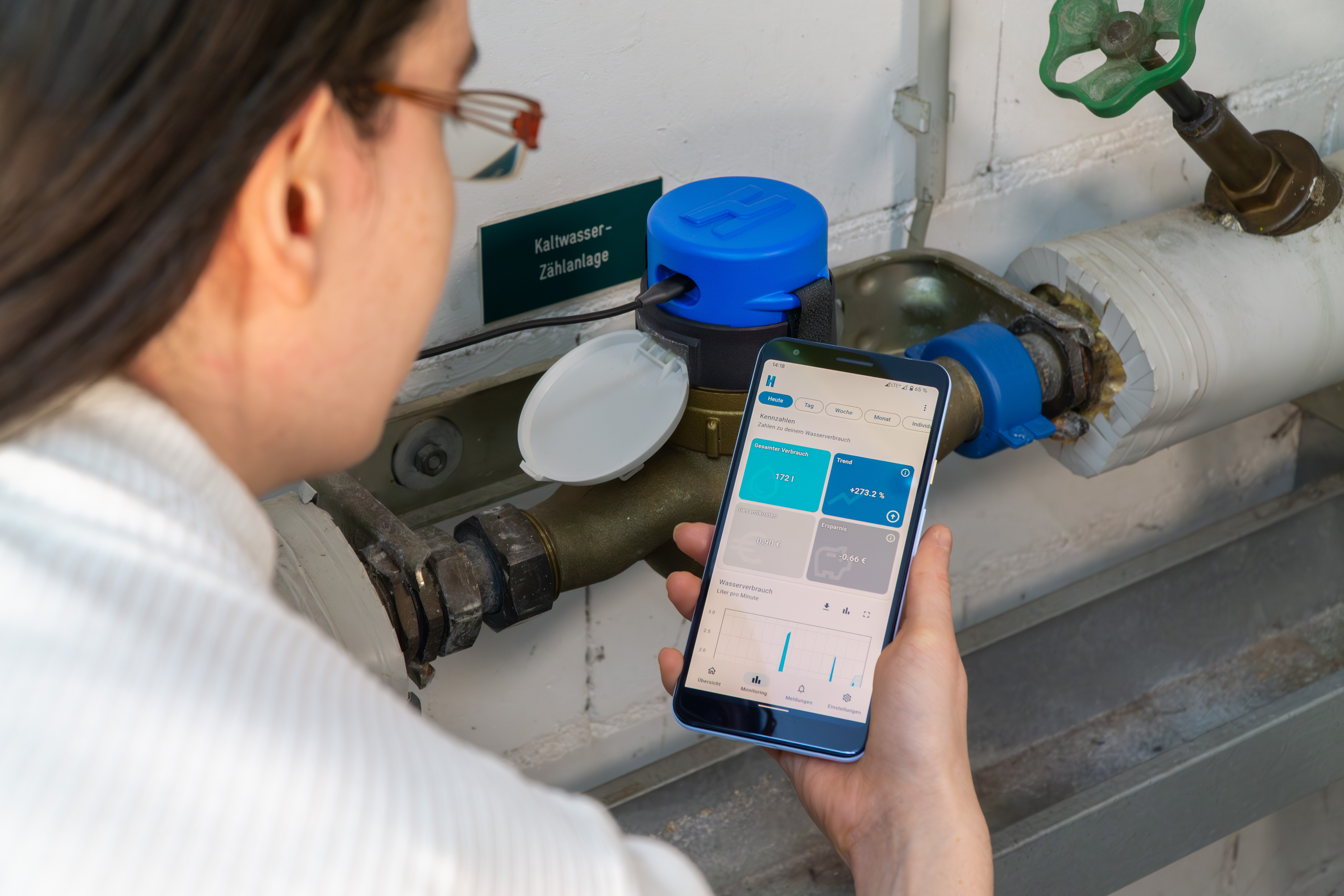 Person schaut auf eine Darstellung des eigenen Wasserverbrauchs in der hydrop App, im Hintergrund ist das hydropmeter auf dem Wasserzähler installiert.