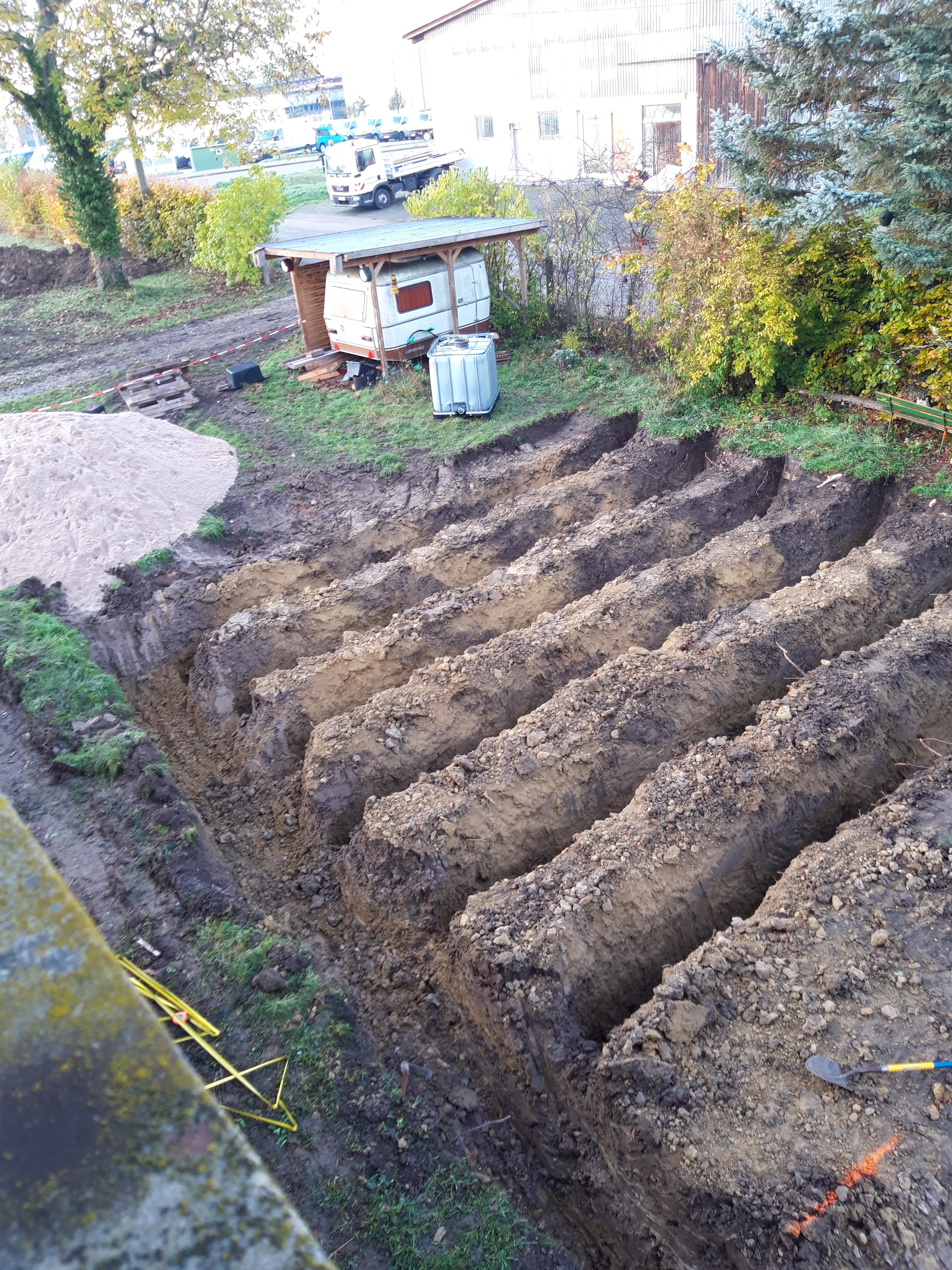 Trenches for setting the trench collectors with backfill material stored on the side