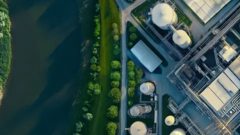 Industrieanlage und Fluss von oben, repräsentieren Klimaschutztechnologie im GreenTech-Bereich
